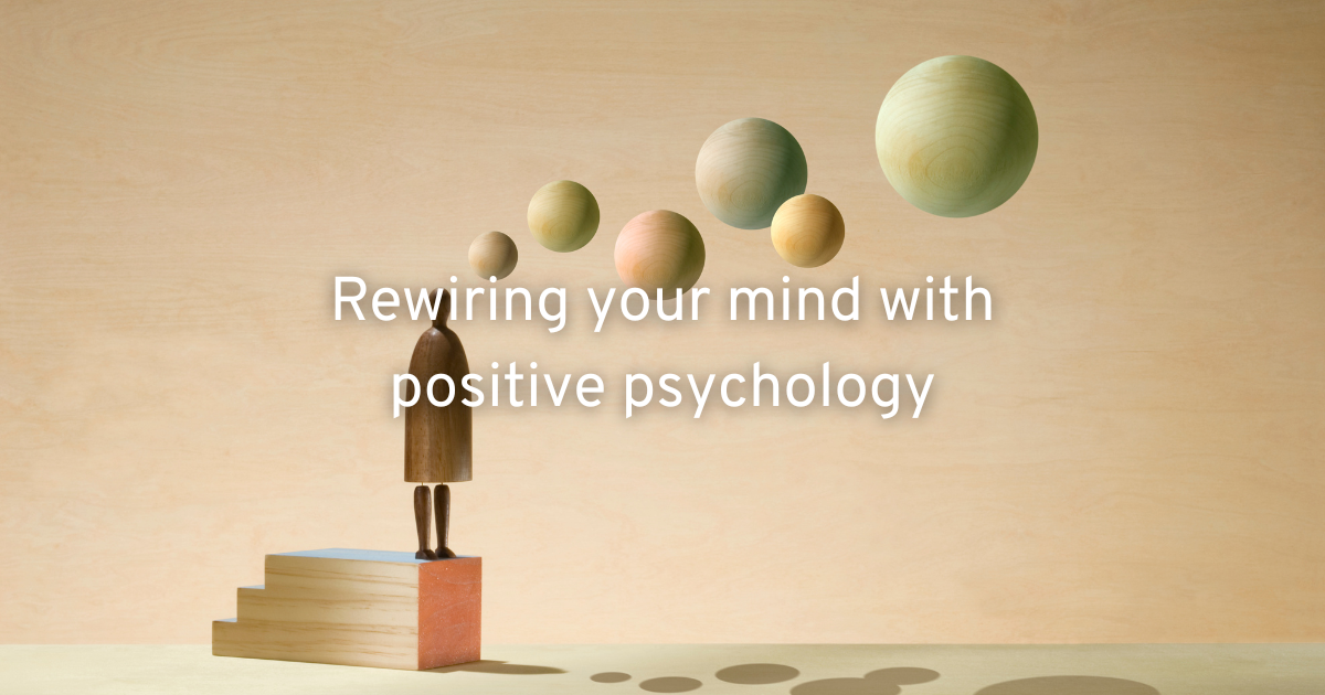 a wooden figure standing on books letting planets of positive thoughts rewriring your brain with positive psychology